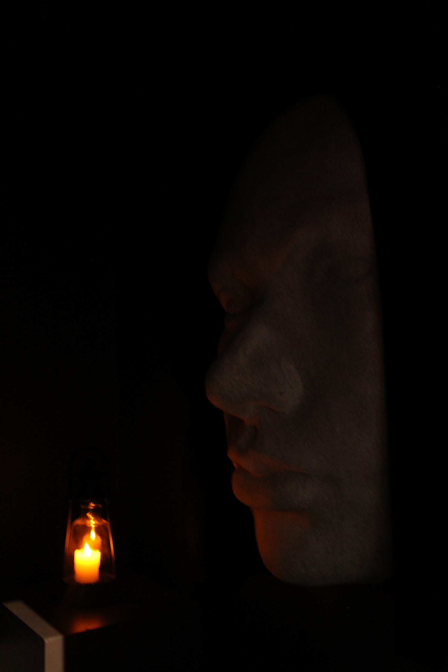 Silhouette of a face with a candle in the dark